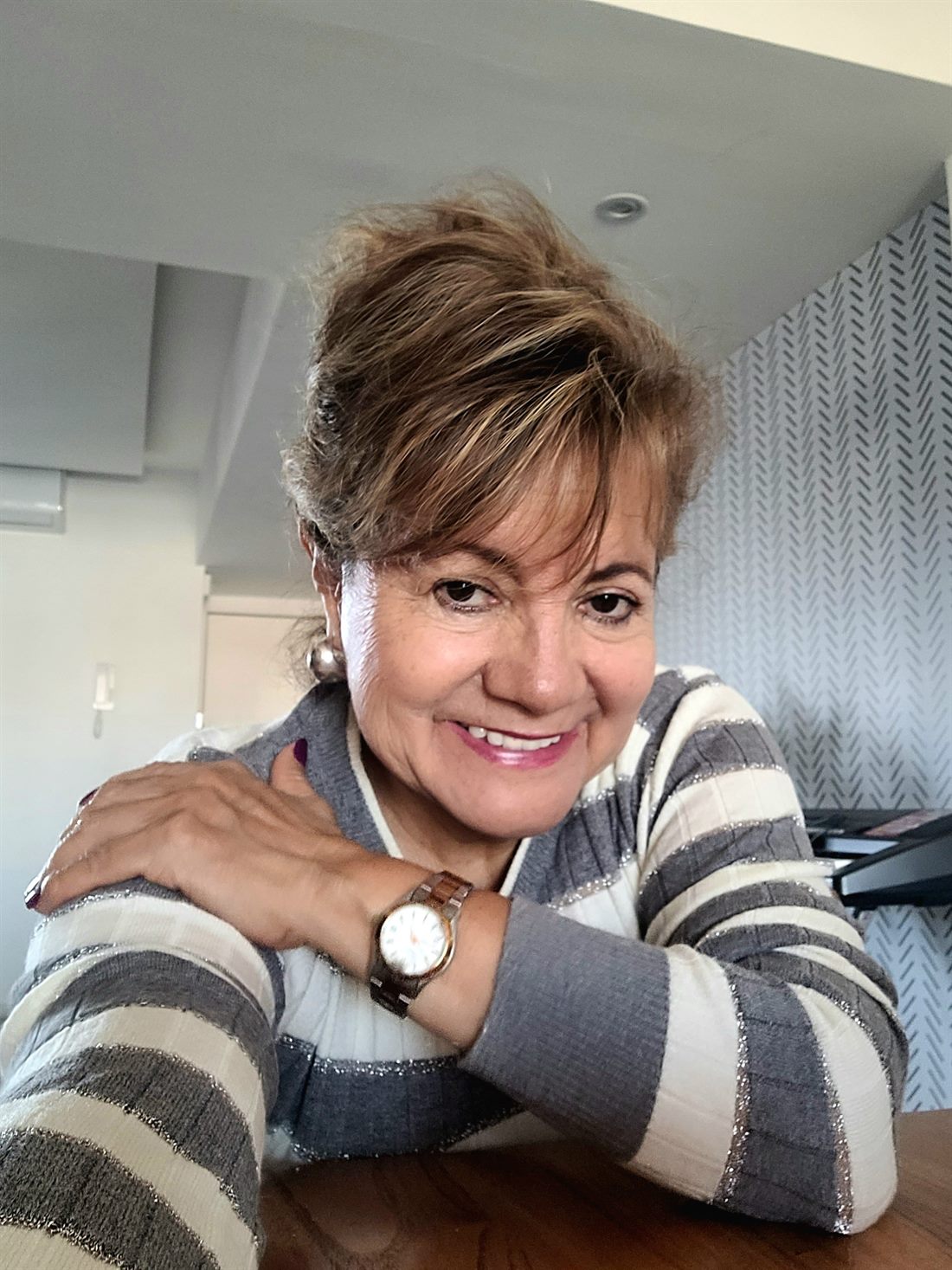 Magui Vargas, de 63 años, sonriendo apoyada en la mesa de su casa
